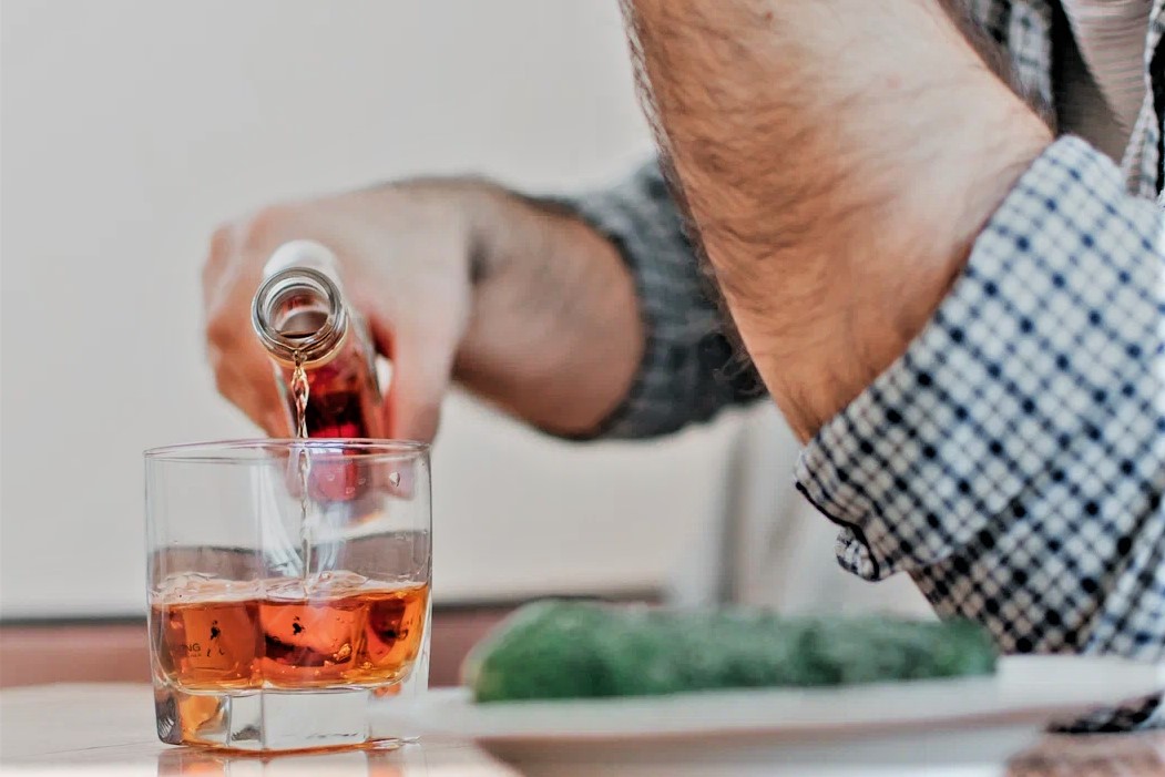 Алкоголик наливает алкоголь в бокал